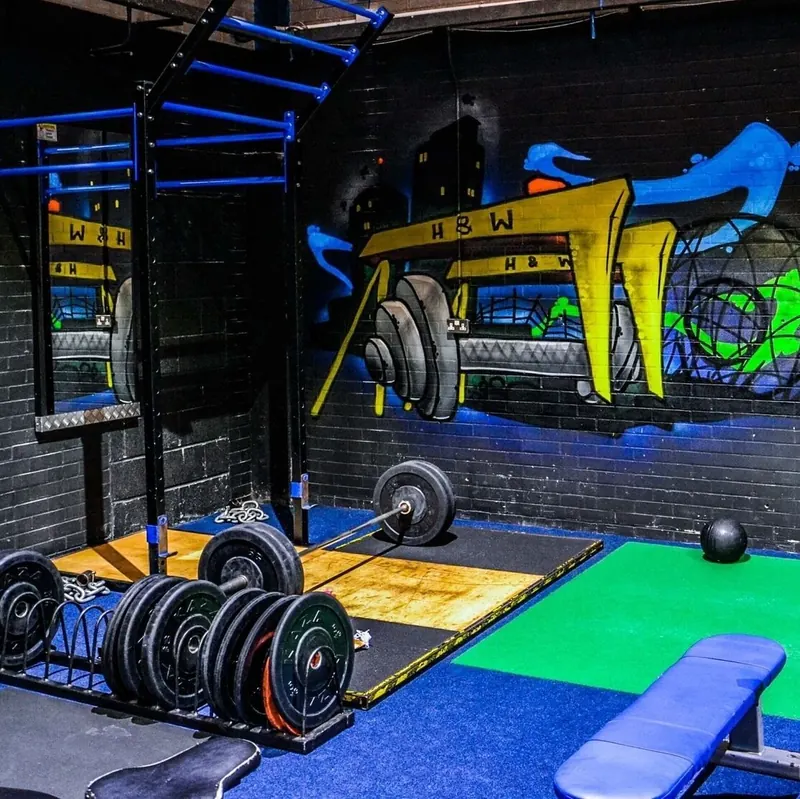 strength training area with mural and lifting platform. — Revolution Fitness